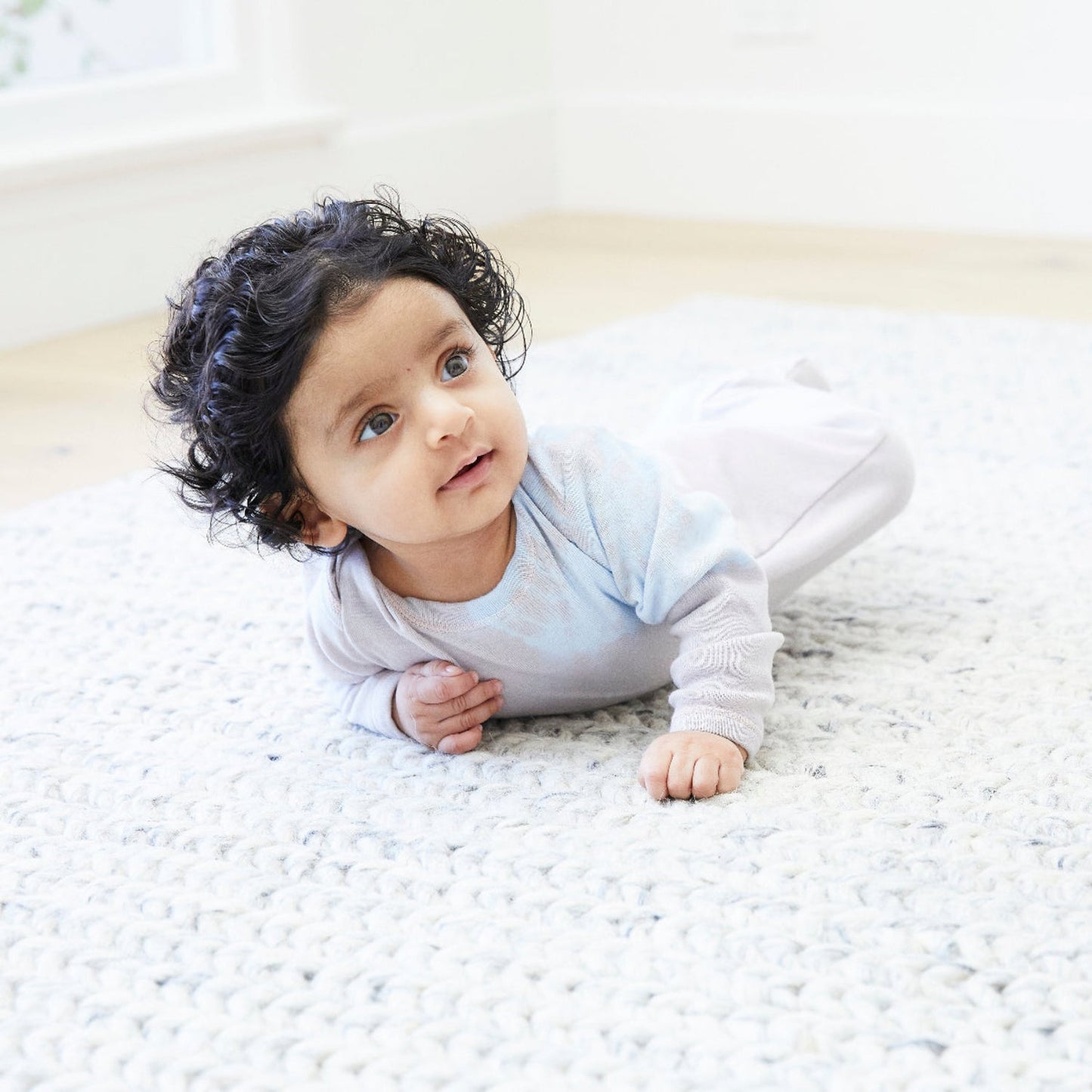 Baby lying on a white blanket with a blurred background