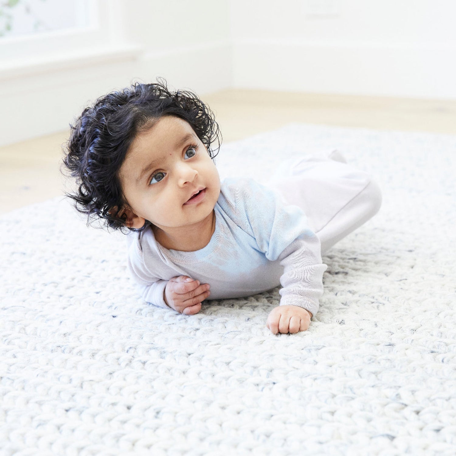 Baby lying on a white blanket with a blurred background