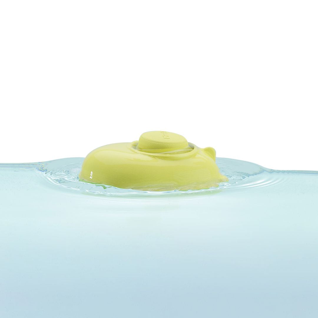 Green rubber duck floating on water with a white background