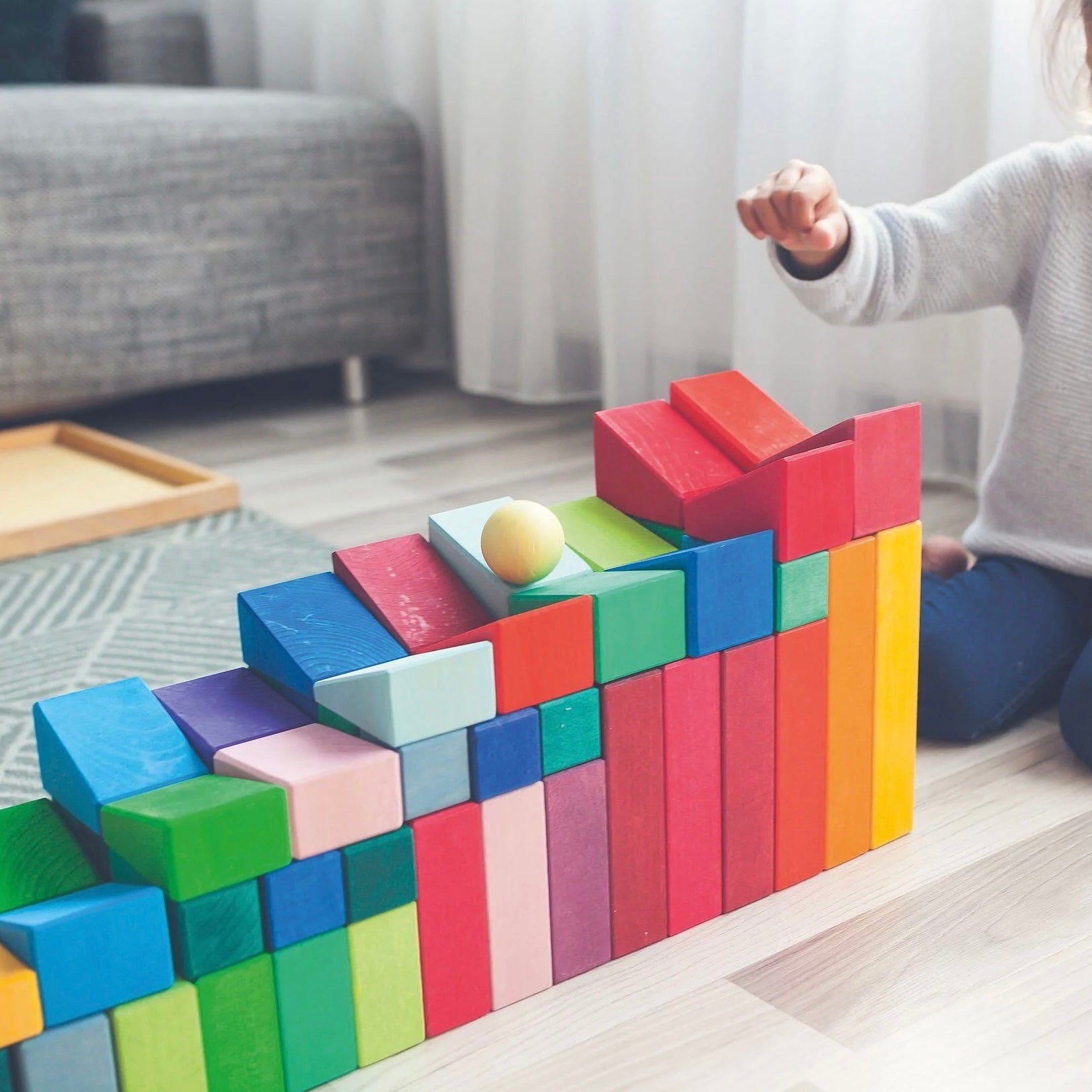 Child playing with colorful building blocks in a living room.