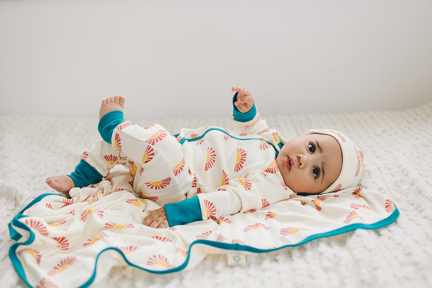 Baby doll wrapped in a colorful blanket on a soft surface