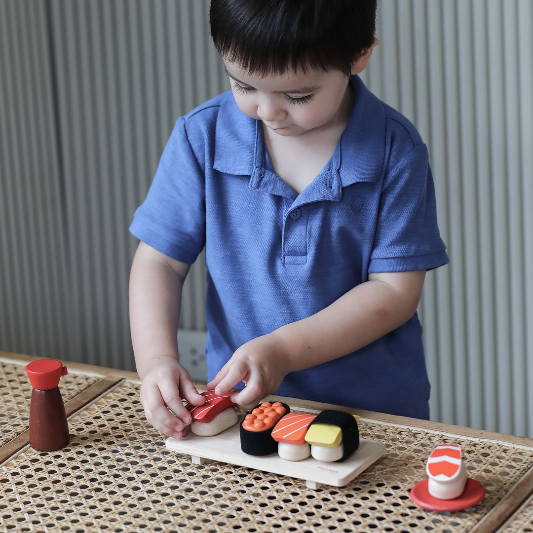 Child playing with a toy sushi set on a table