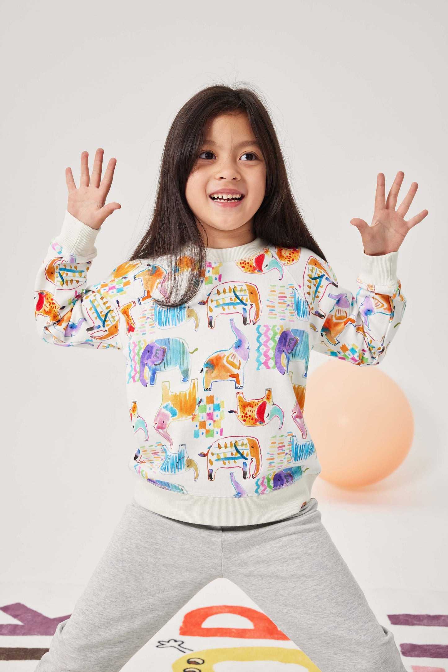 Child wearing a colorful animal-patterned sweatshirt on a white background