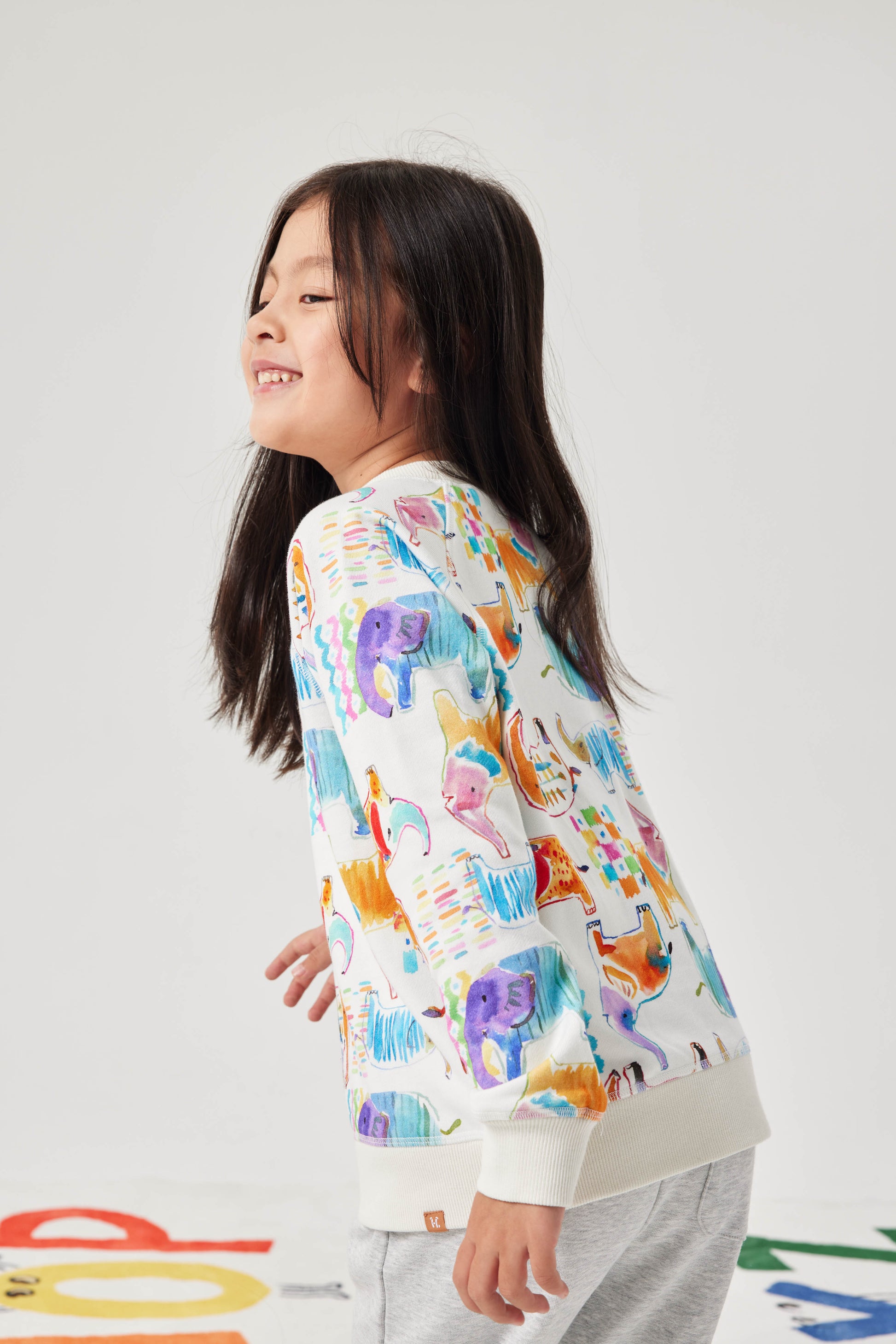 Child wearing a colorful sweater with cartoon designs on a white background