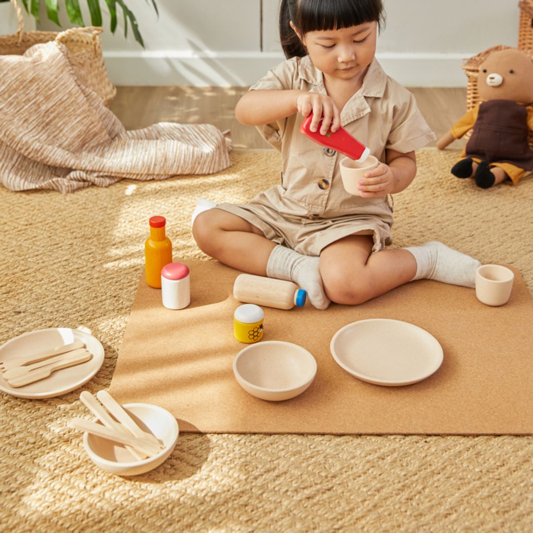 Child playing with toy kitchen items on a mat indoors