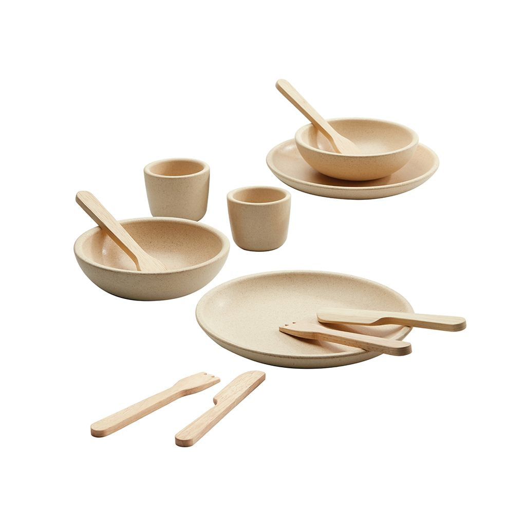 Set of natural-colored ceramic dishes with wooden utensils on a white background