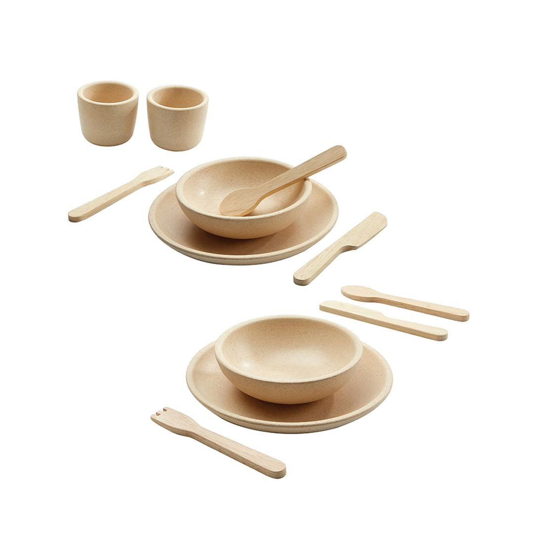 Set of wooden dining utensils including bowls, spoons, and cups on a white background