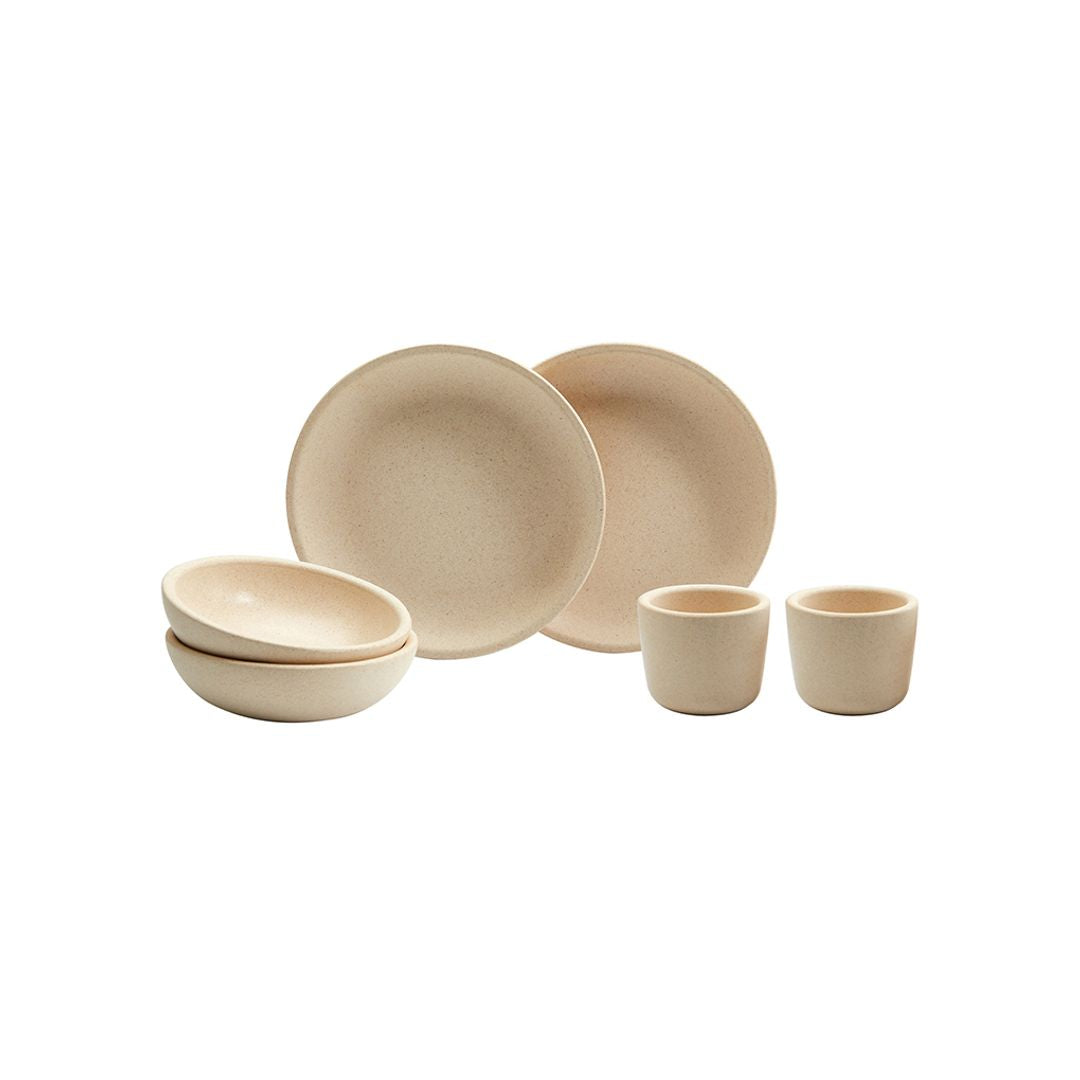 Set of beige ceramic dishes including bowls and cups on a white background