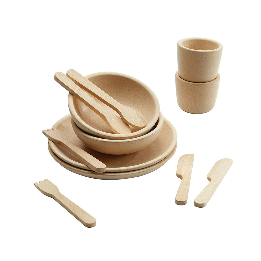 Set of wooden dining utensils including bowls, cups, and cutlery on a white background