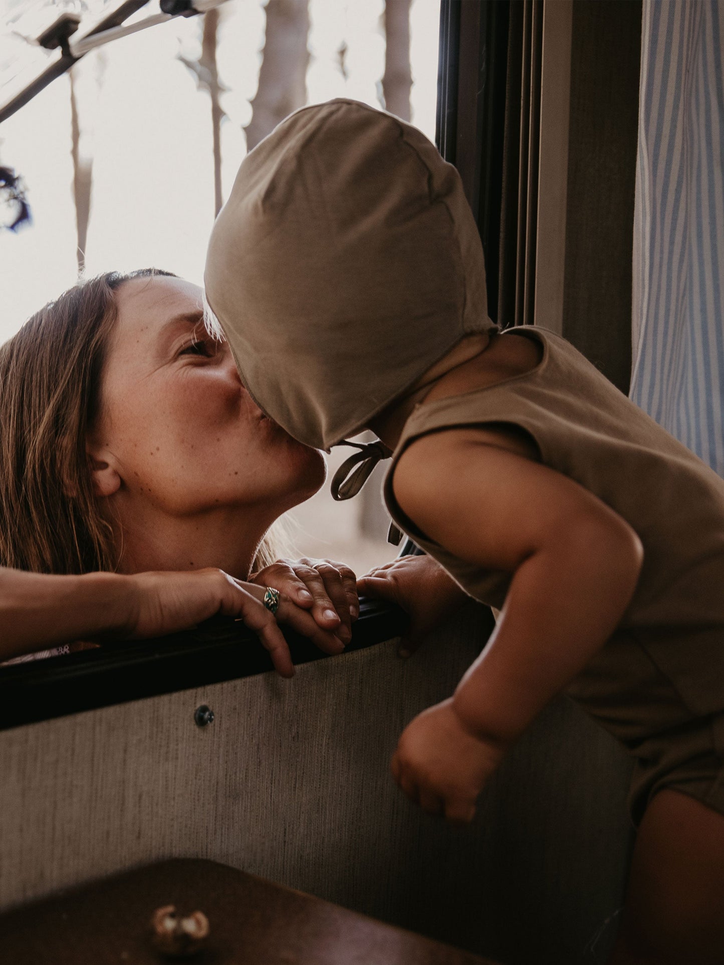Woman and child sharing a kiss near a window with blurred background