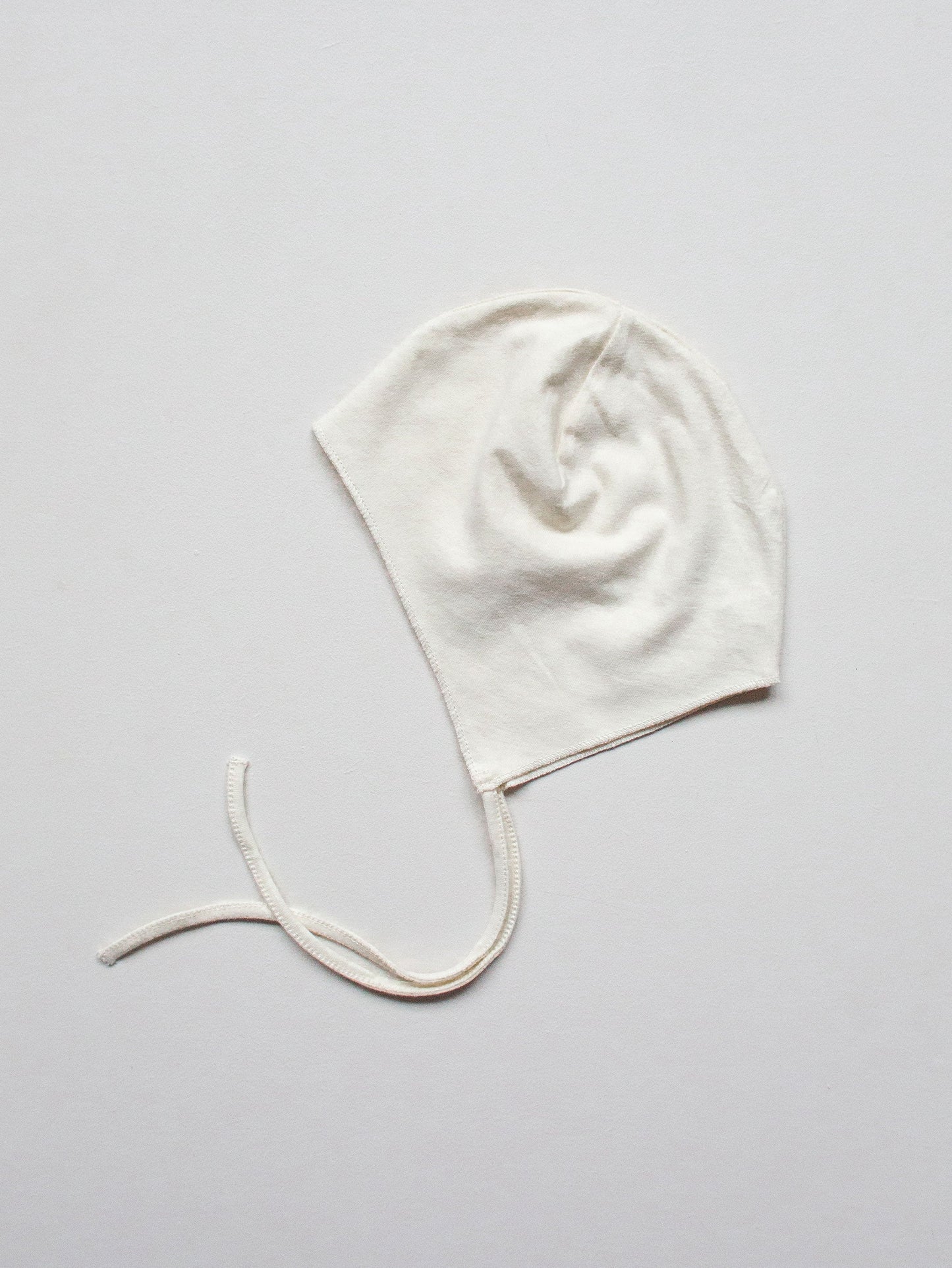 White baby bonnet on a light gray background