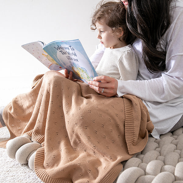 Woman reading a book to a child on a soft surface
