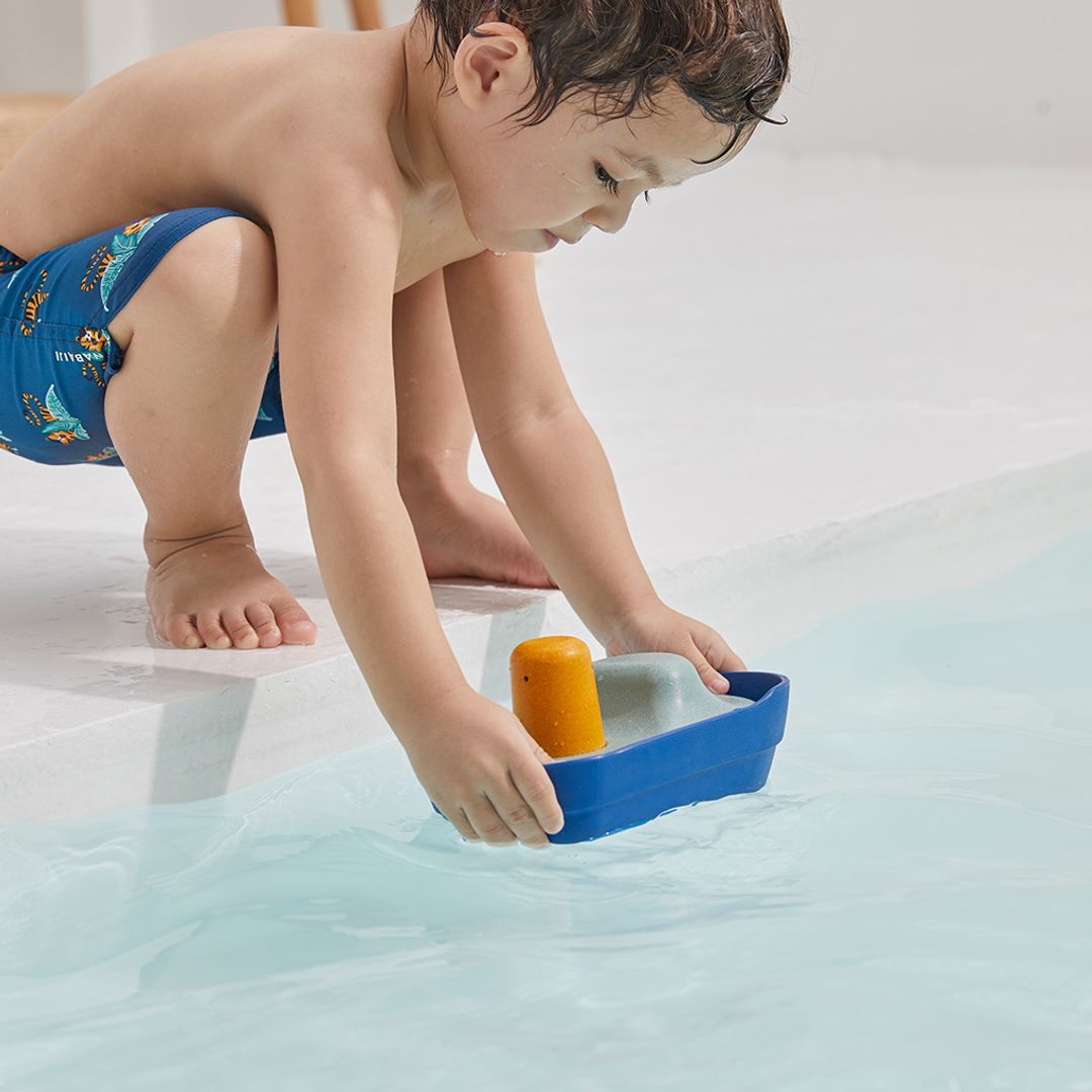 Child playing with a blue toy in a bathtub filled with water.