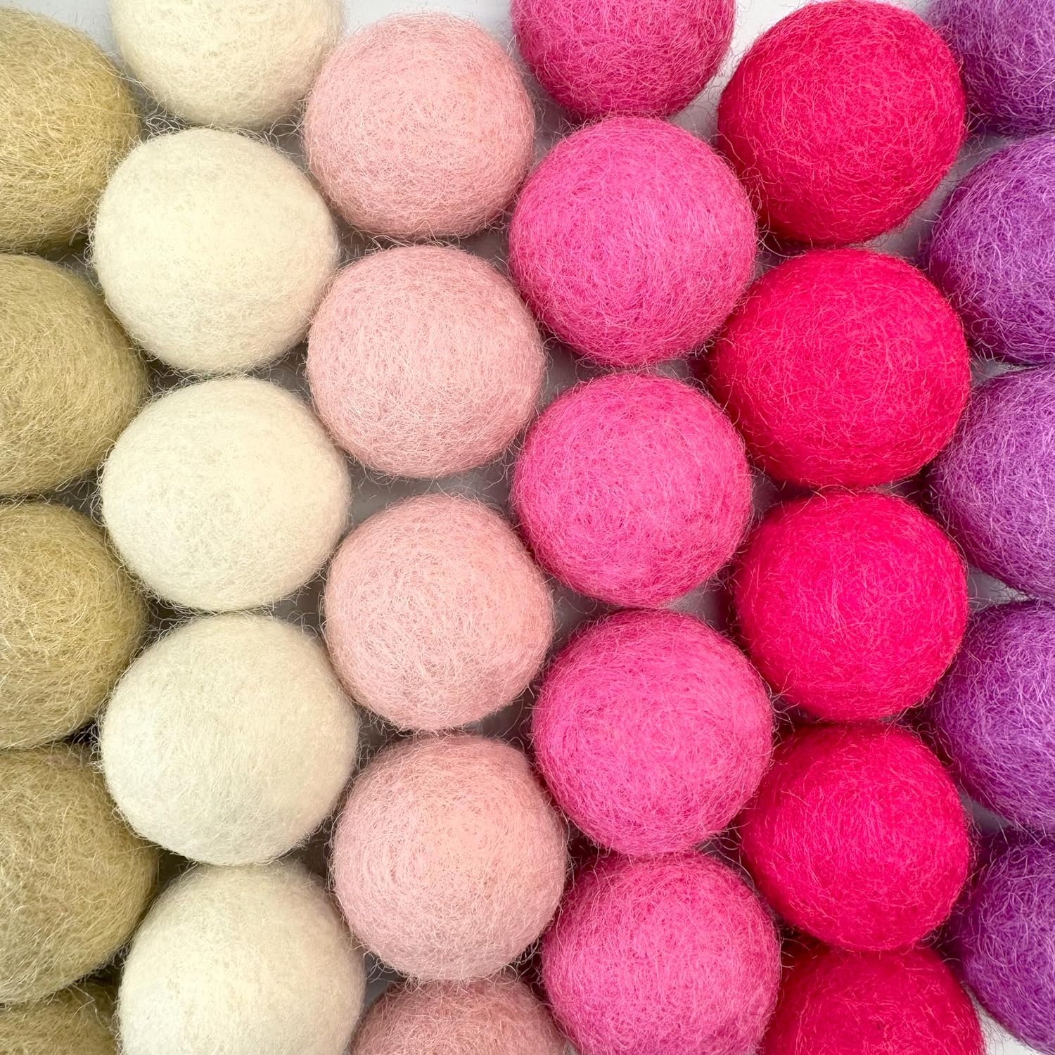 Colorful felt balls in pink, purple, and green on a white background