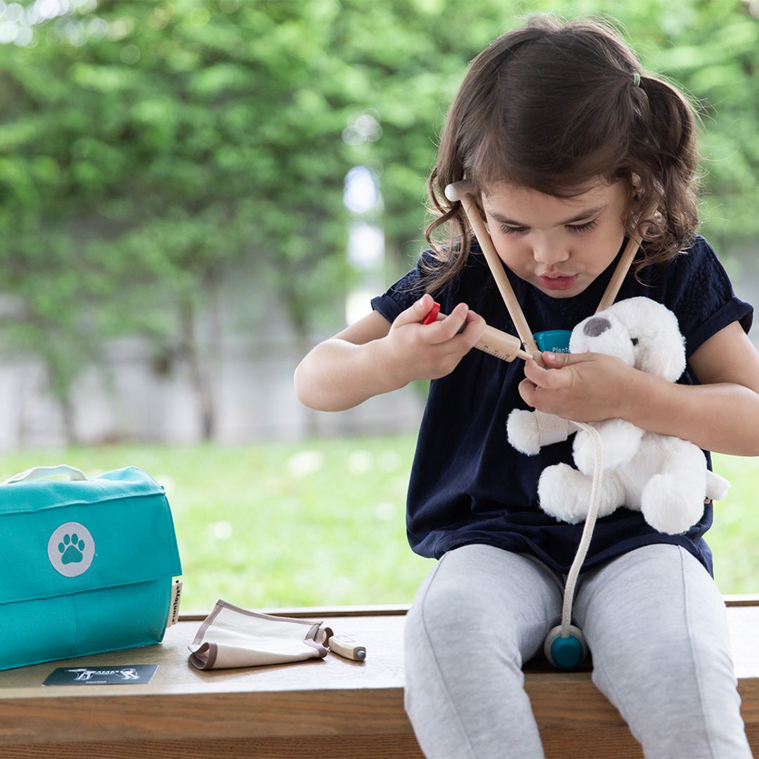 Child playing with toy doctor's kit outdoors