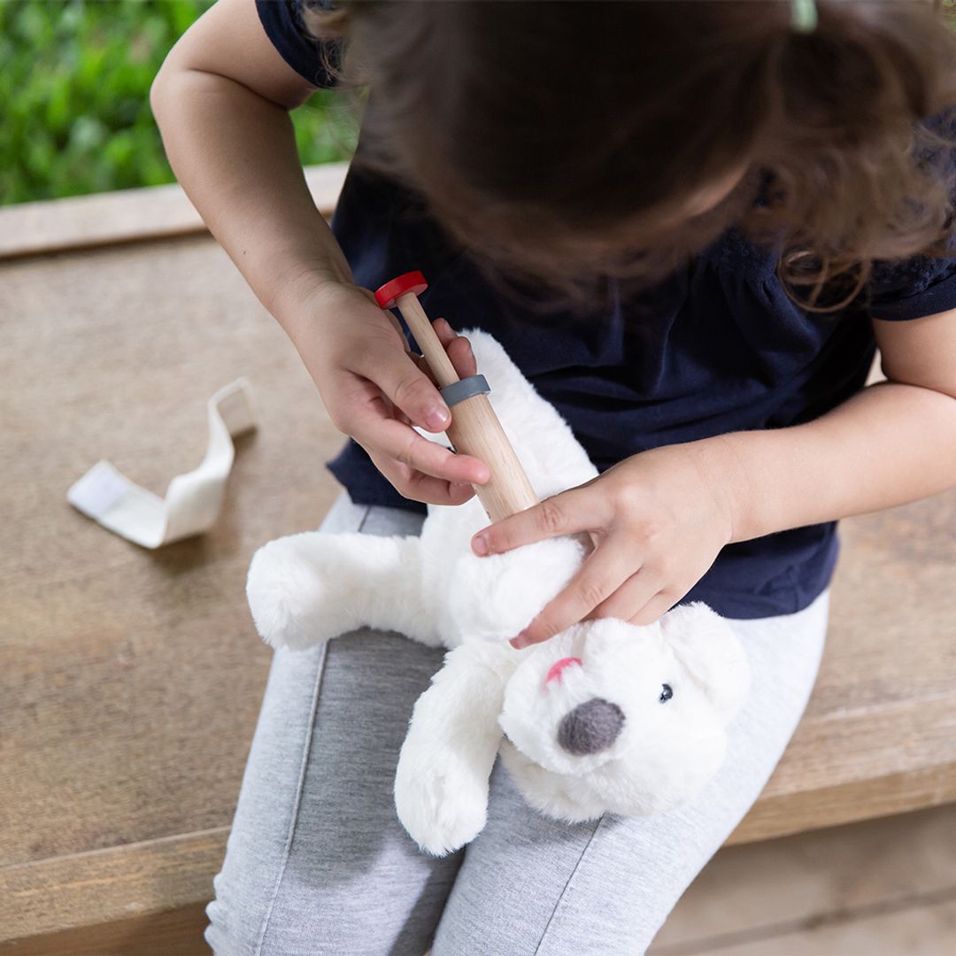 Child playing with a toy hammer on a stuffed animal outdoors