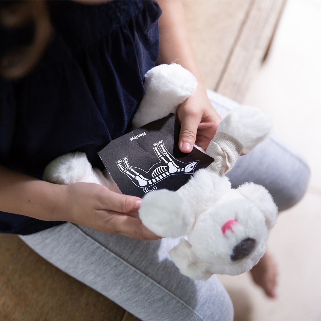 Person holding a white plush toy and a card with a design on it.