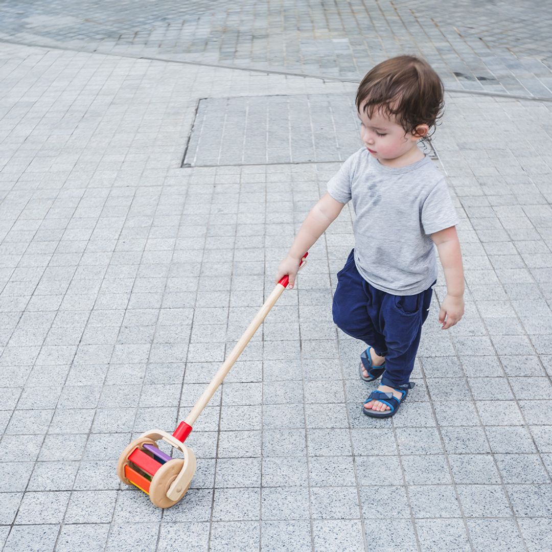 Child holding a toy broom on a tiled pavement