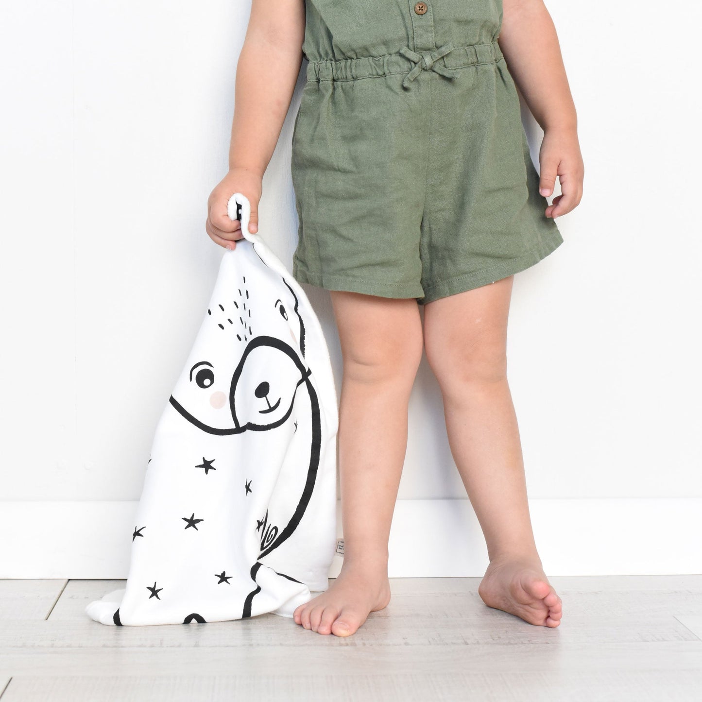 Child holding a white towel with a black bear design against a white background