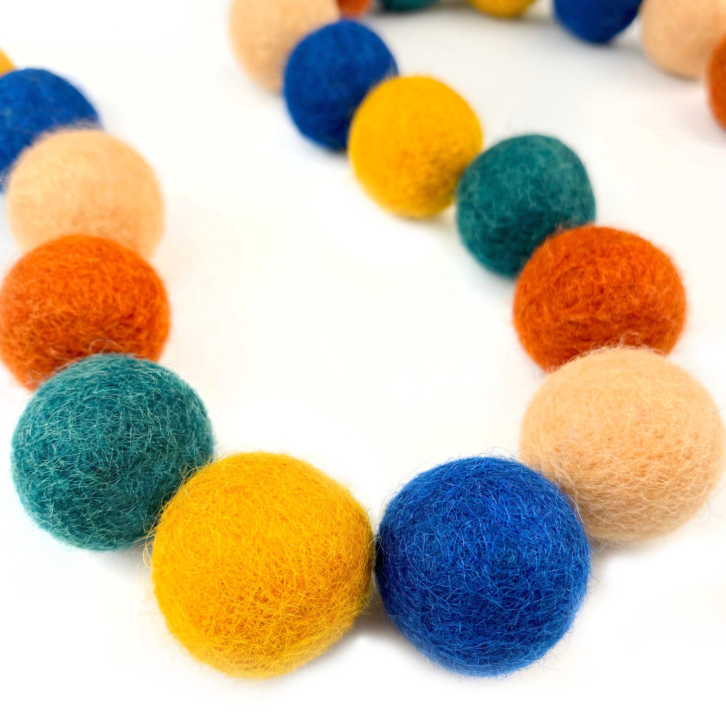 Colorful felt ball garland on a white background