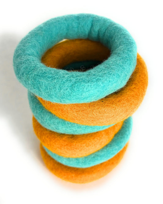 Stack of turquoise and orange felt rings on a white background