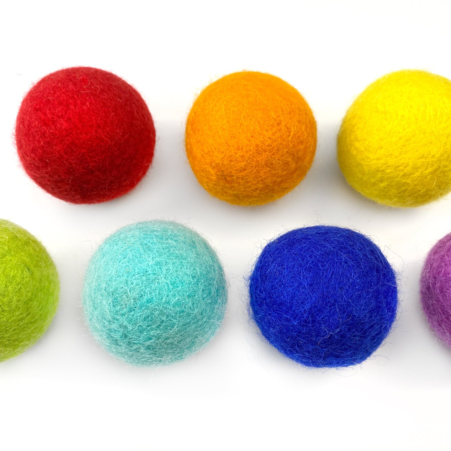 Colorful felt balls arranged in a row on a white background