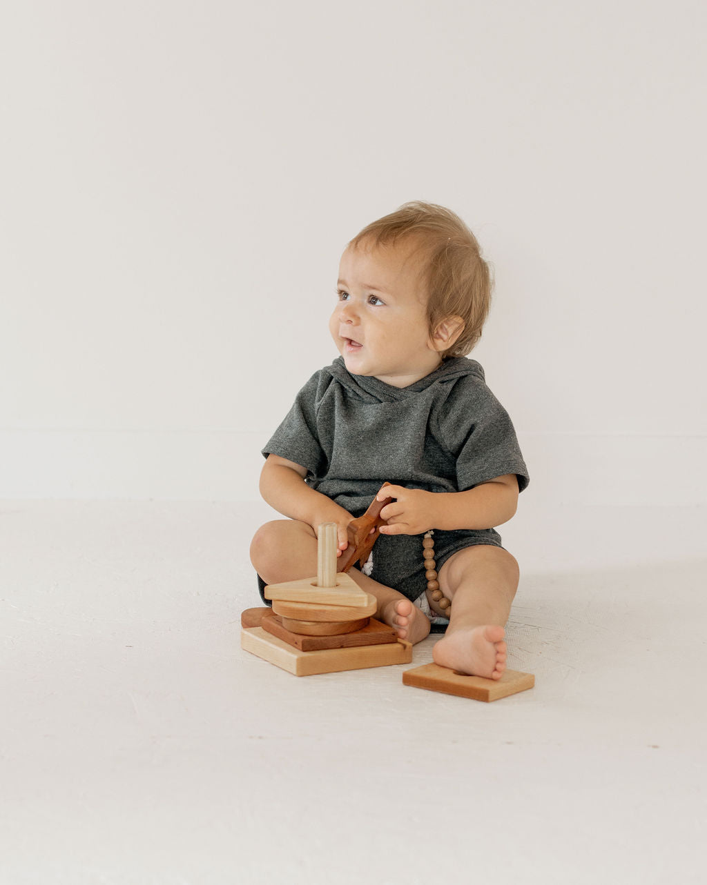 Baby sitting on a white floor with wooden toys