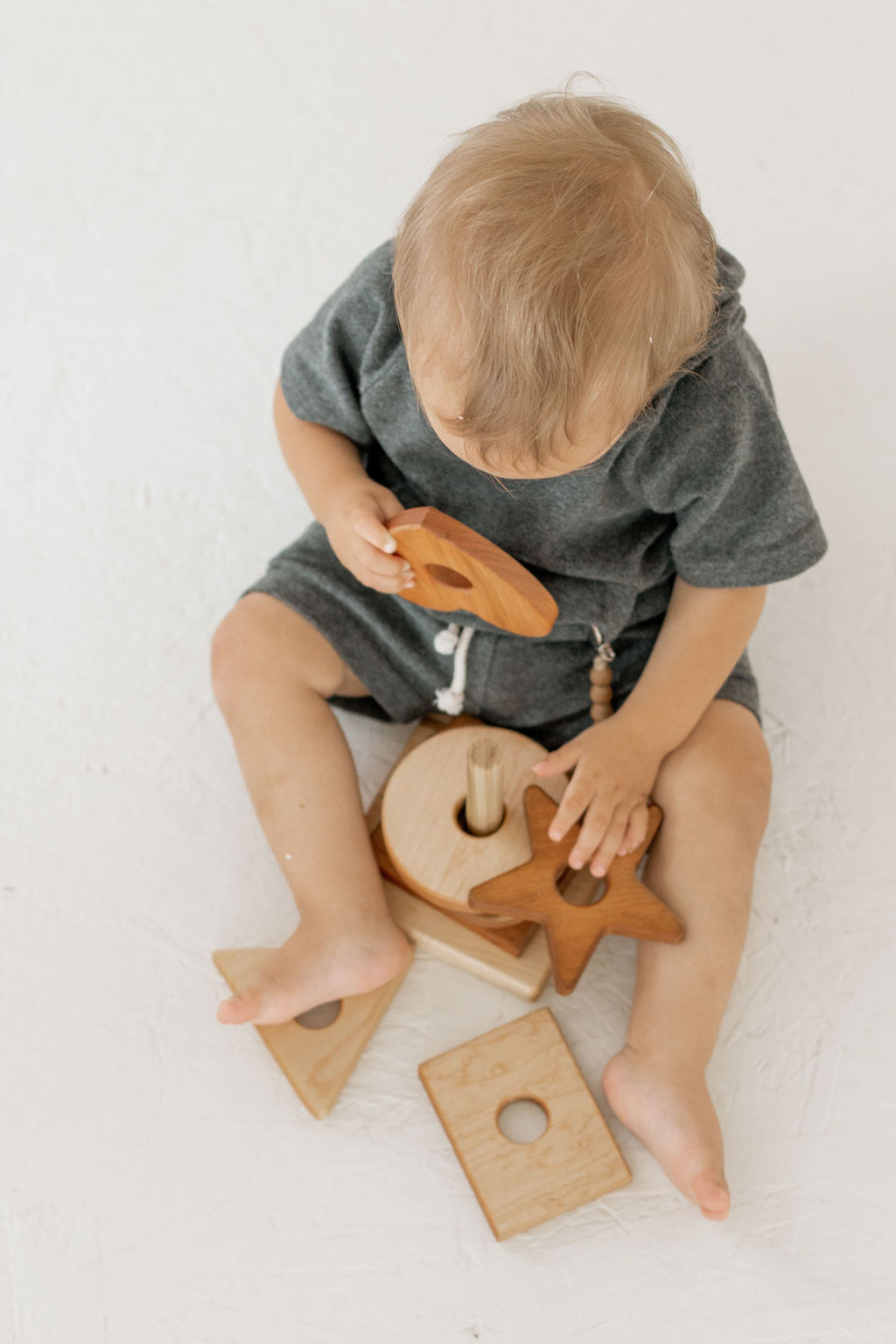 Child playing with wooden toys on a white surface