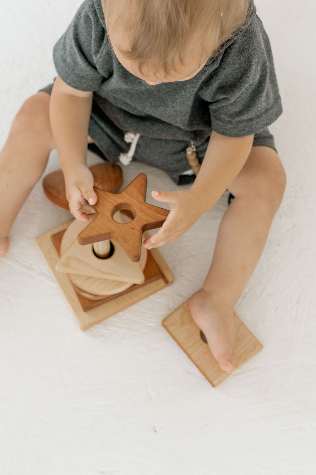Child playing with wooden toys on a white surface