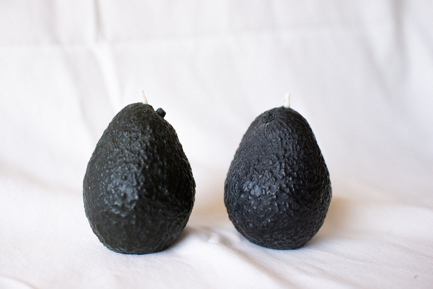 Two black avocados on a white background