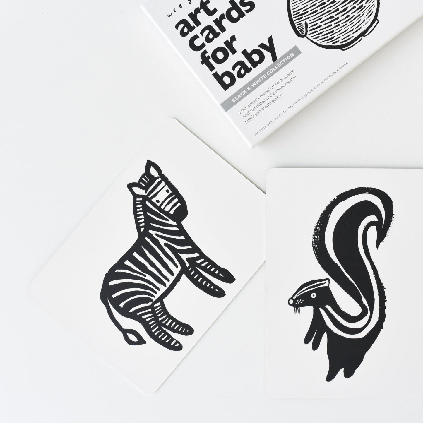 Black and white animal illustrations on a white surface with a book titled 'Art Cards for Baby' in the background.