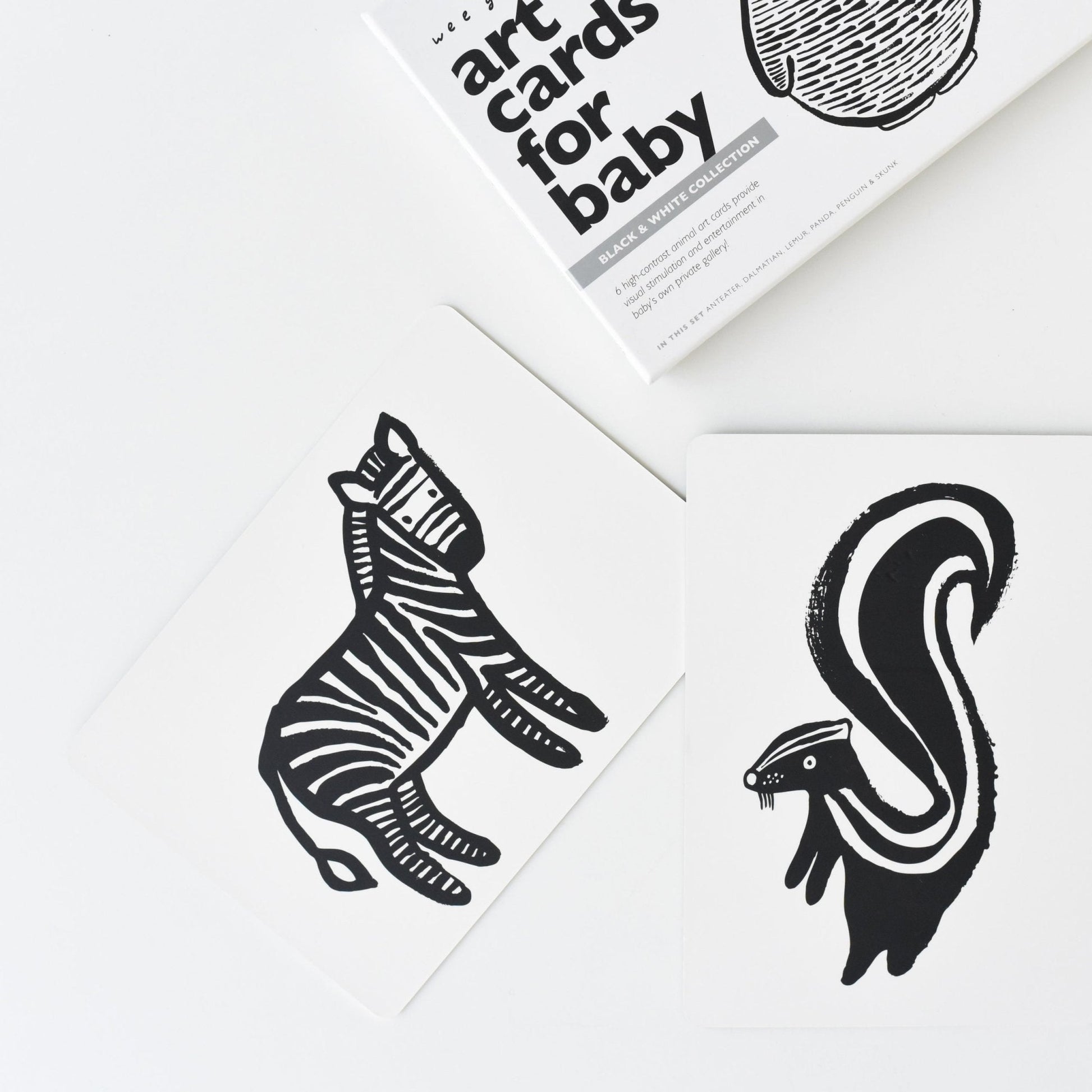 Black and white animal illustrations on a white surface with a book titled 'Art Cards for Baby' in the background.
