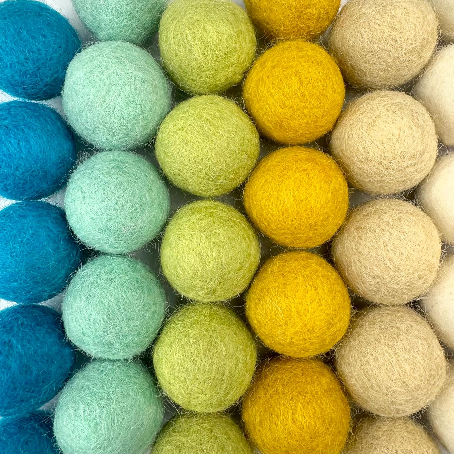 Colorful felt balls arranged in a pattern on a white background