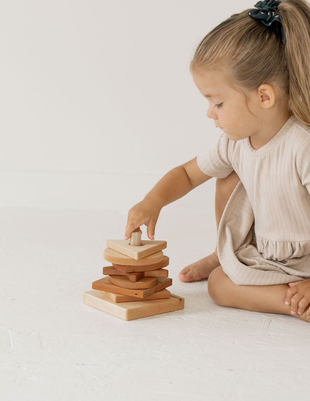 Child playing with wooden stacking blocks on a light background