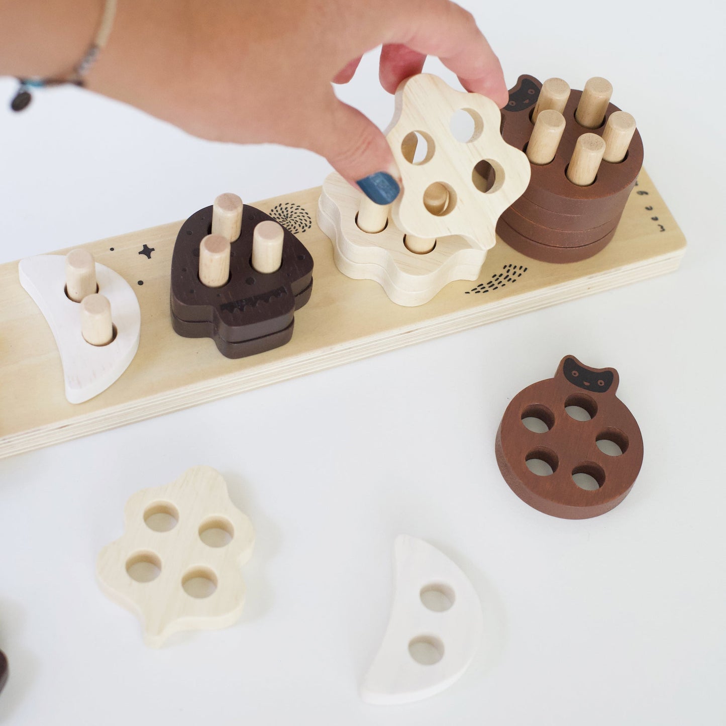 Wooden shape sorting toy with a hand interacting with it on a white background