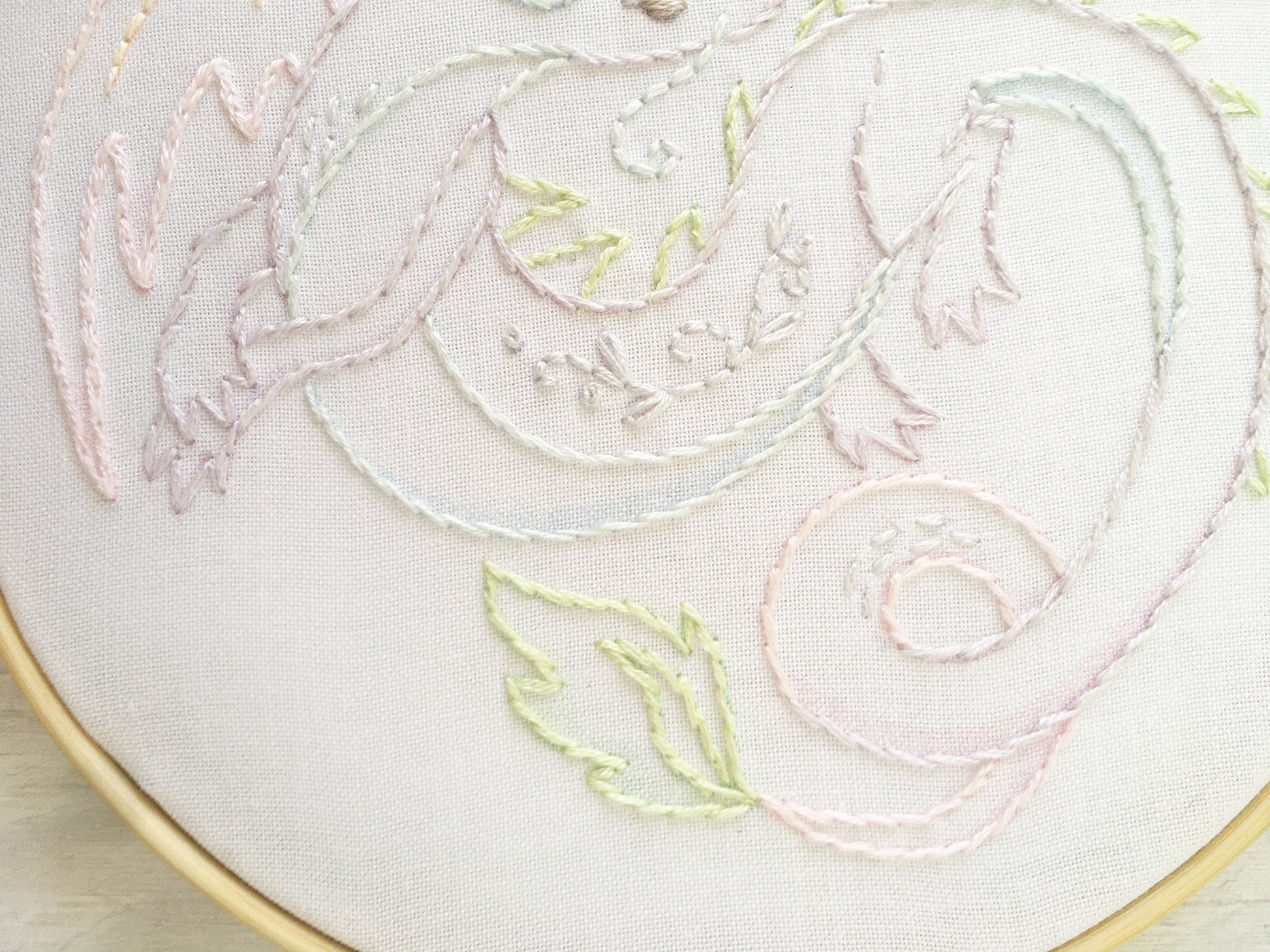 Close-up of embroidered floral design on white fabric with gold hoop