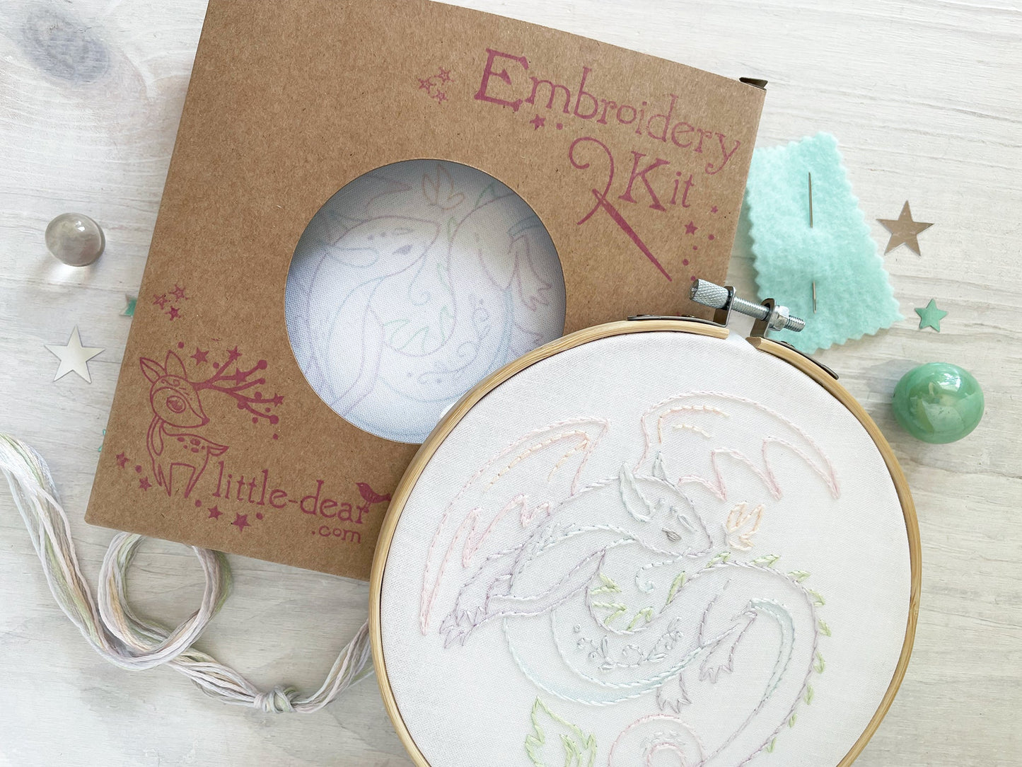 Embroidery kit with a partially completed embroidery design on a wooden surface.