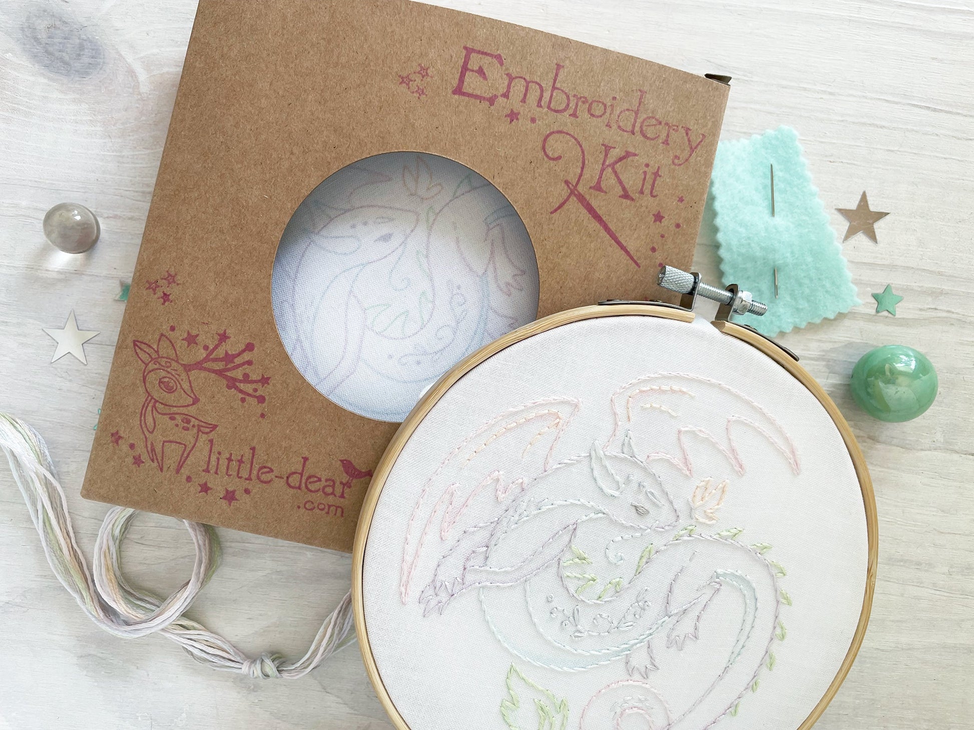 Embroidery kit with a partially completed embroidery design on a wooden surface.