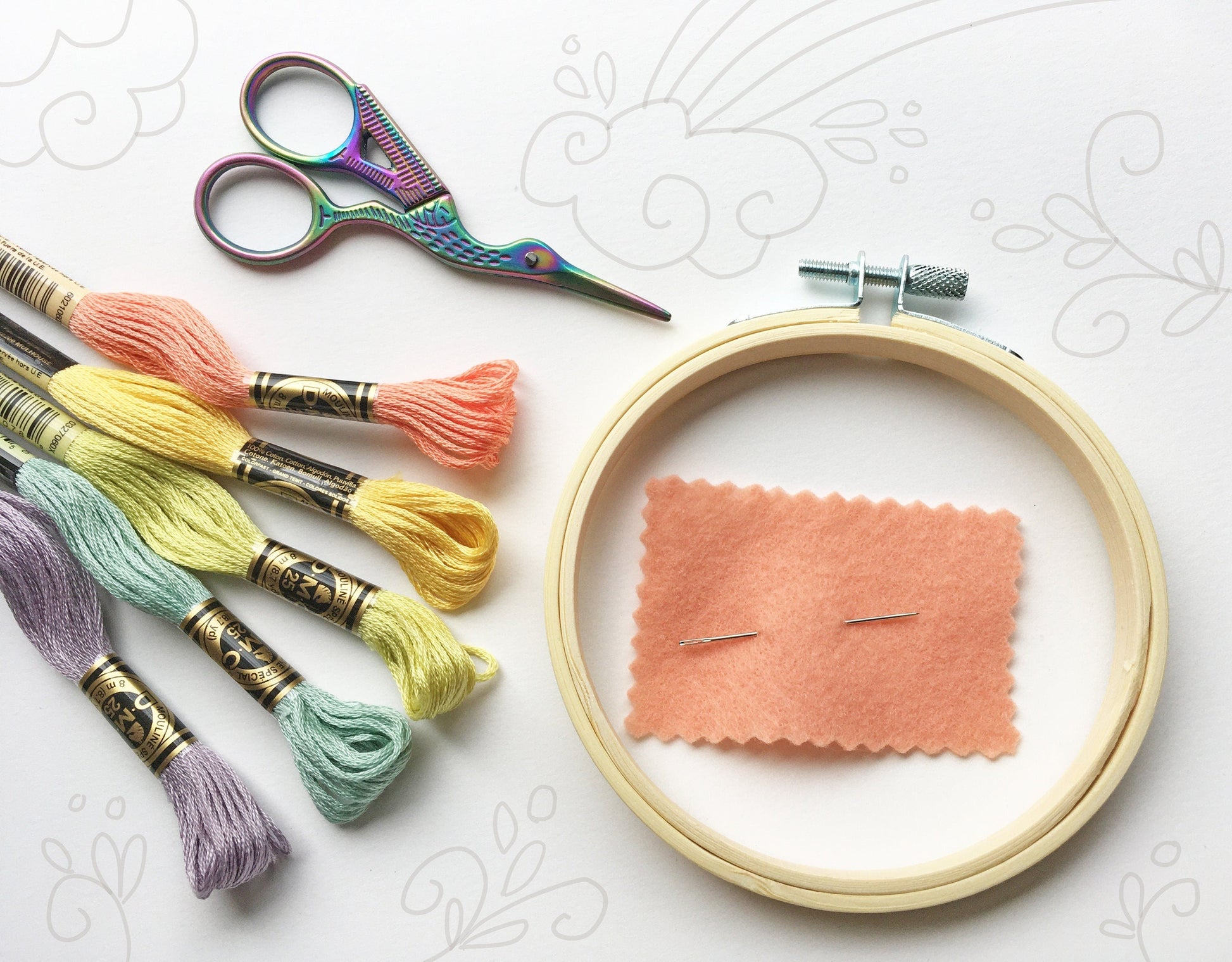 Embroidery hoop with fabric, scissors, and colorful thread on a white background