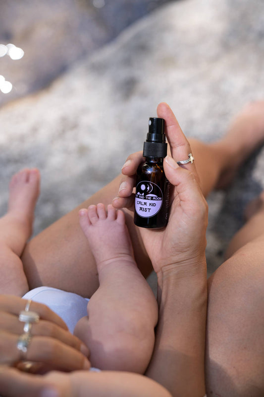 a person holding a baby and a kid calm spray in their hand