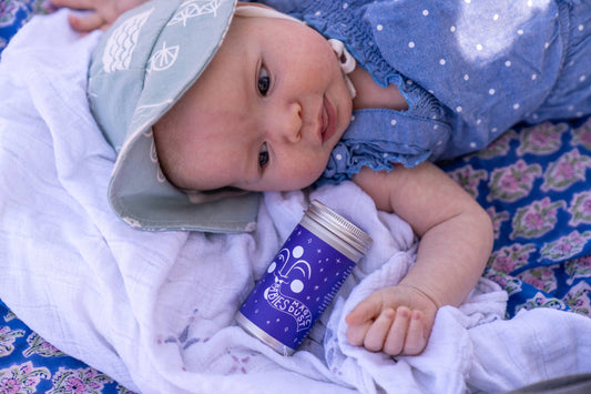 a baby laying on a blanket next to a container of babies magic dust