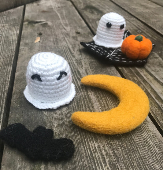 Crocheted ghost, moon, and pumpkin on a wooden surface