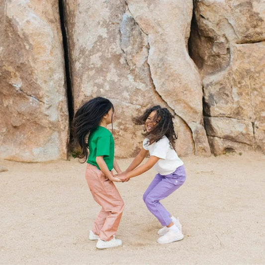 Two children holding hands in front of a rocky background