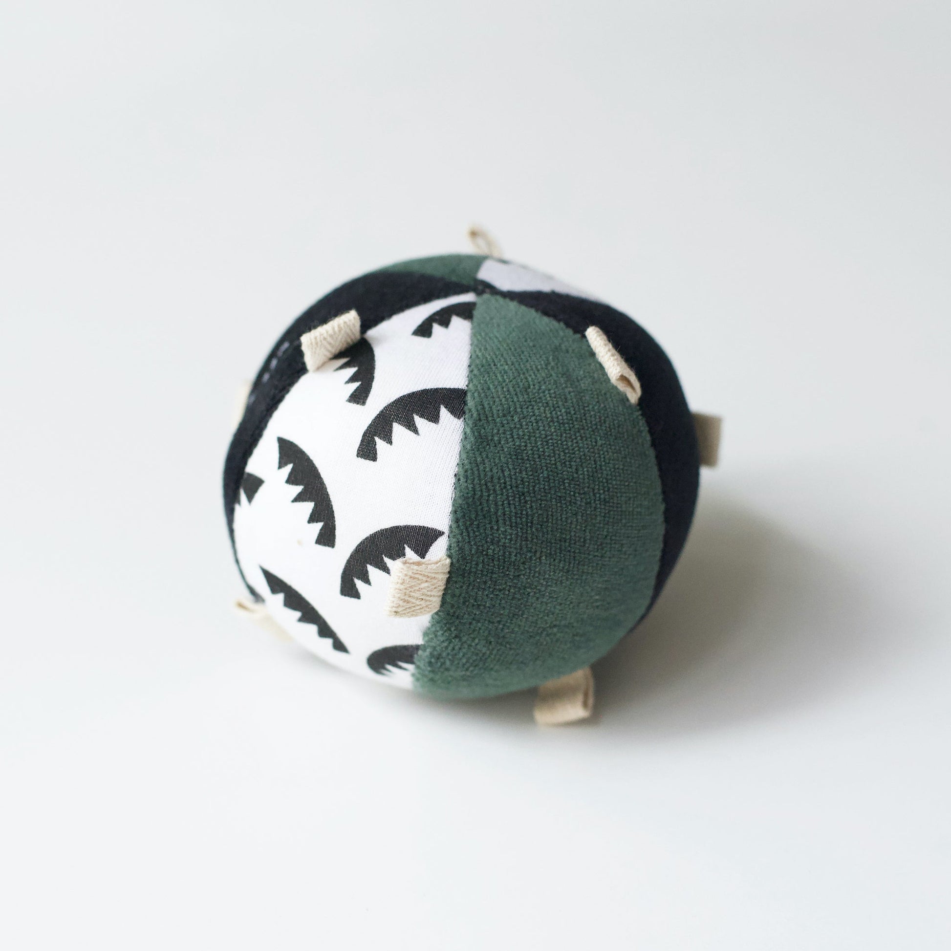 Round fabric toy with black and white pattern on a white background