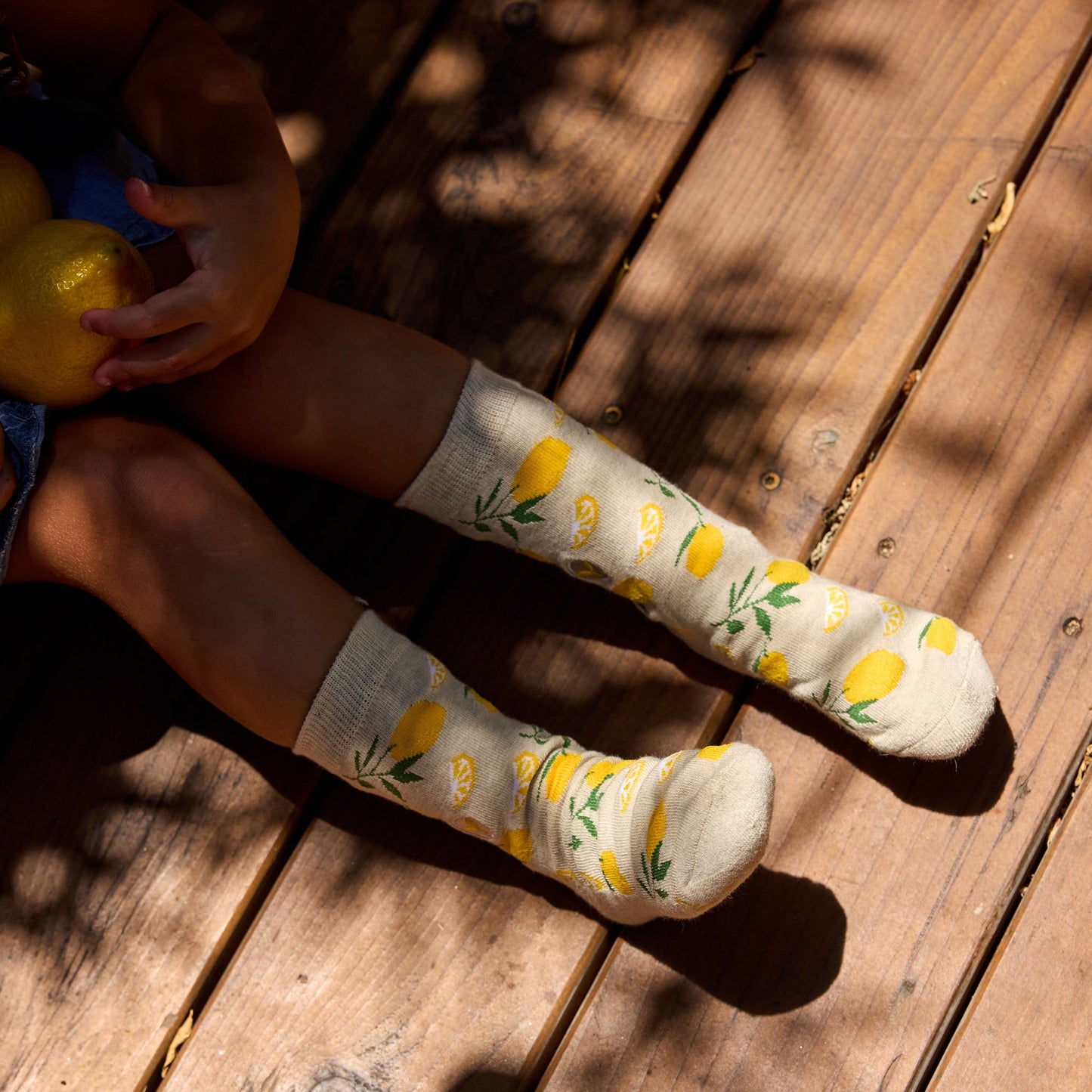 Person wearing socks with lemon pattern on a wooden floor