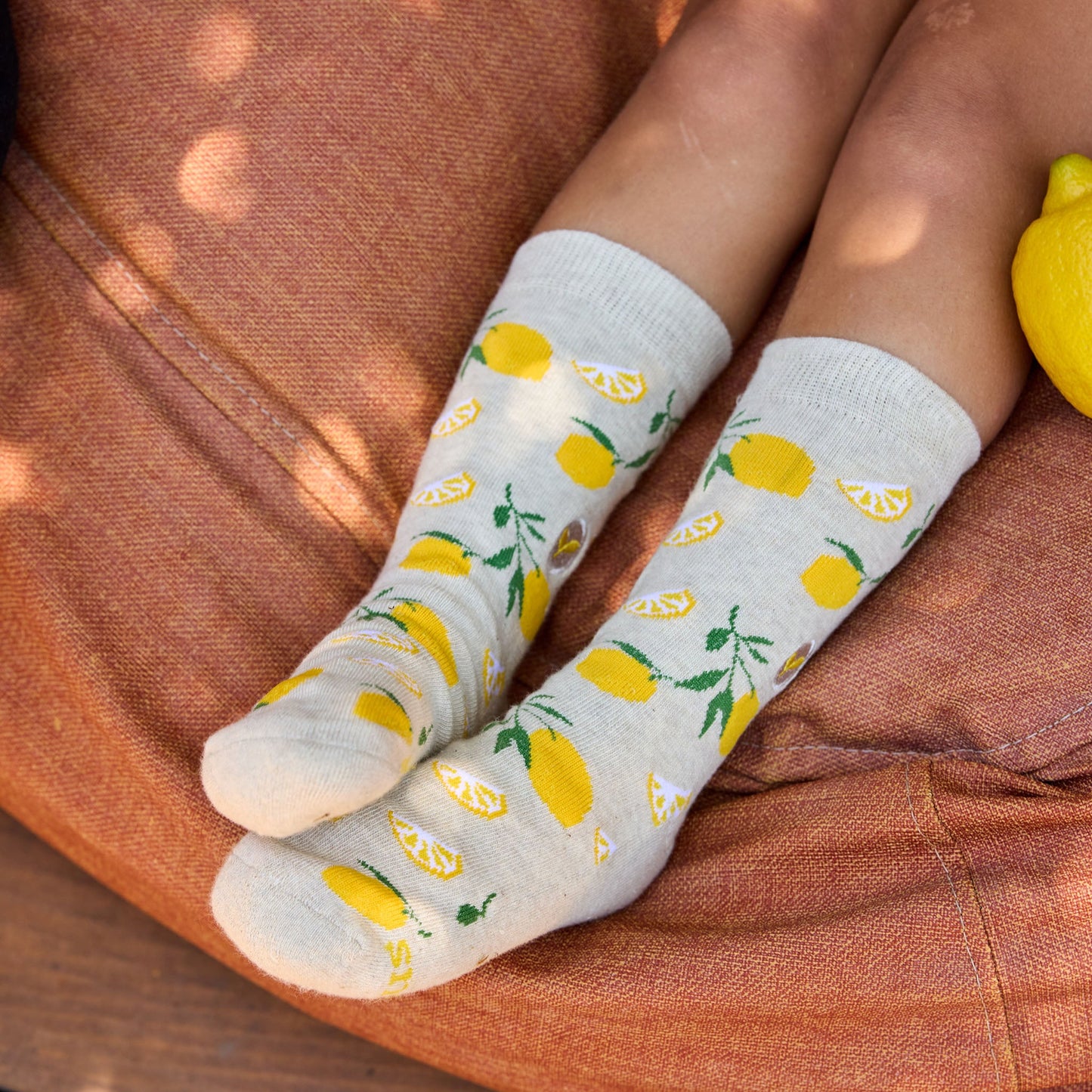 Person wearing socks with lemon pattern on a brown surface