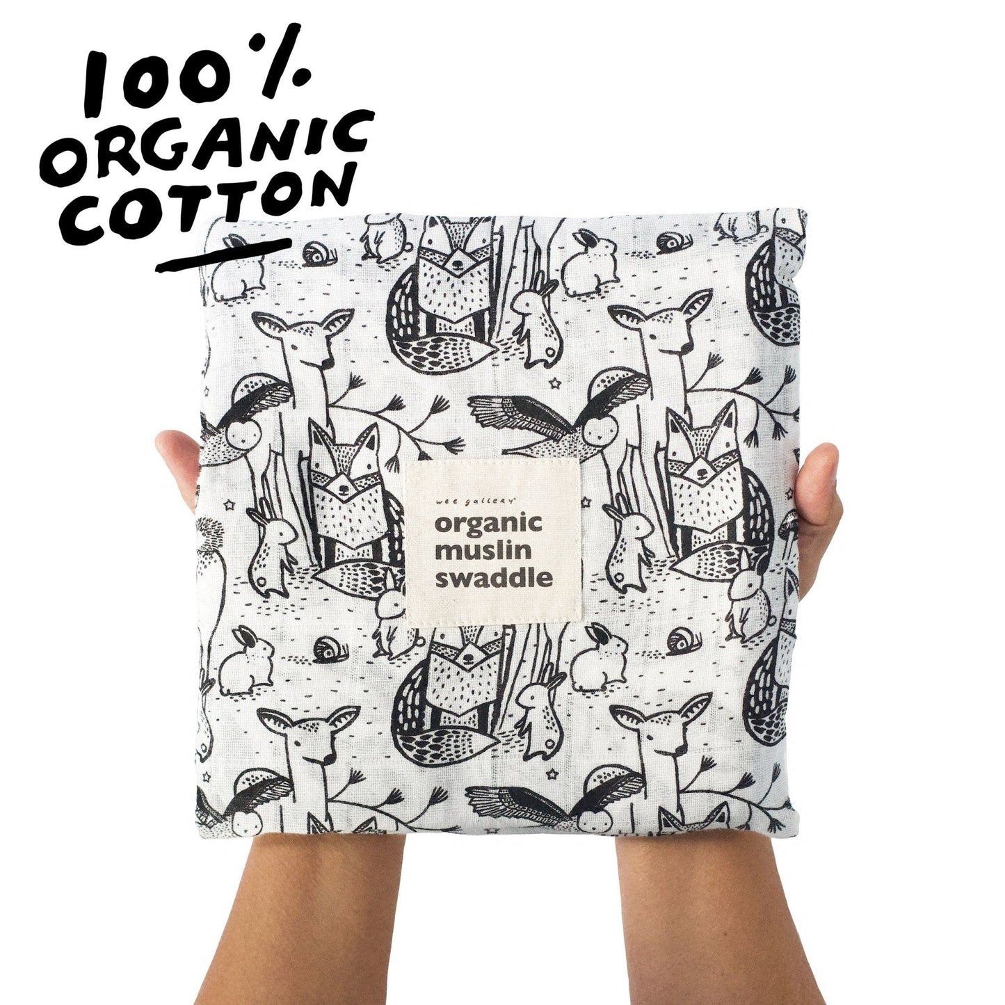 Organic cotton swaddle blanket with animal pattern held by a person, labeled '100% Organic Cotton'.