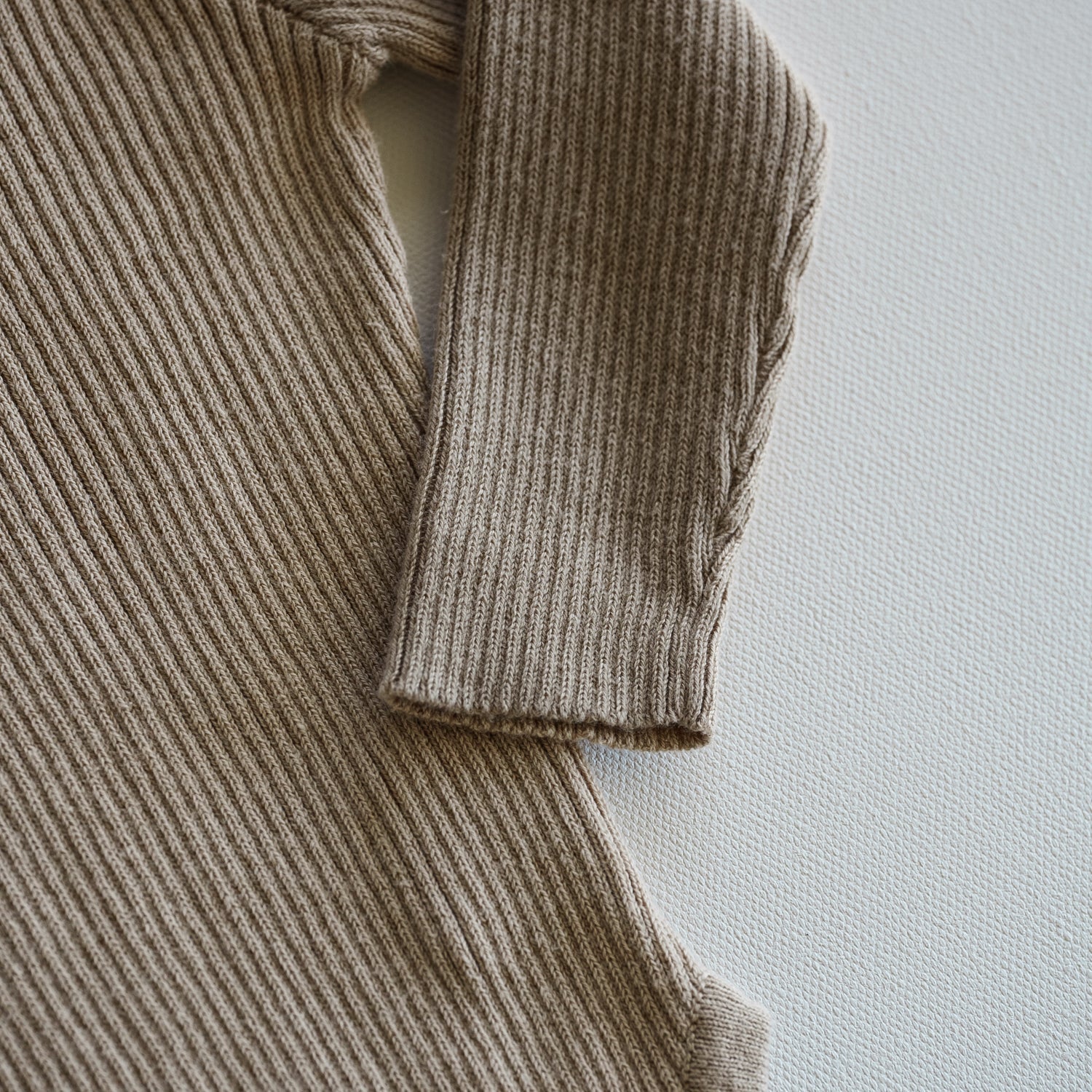 Close-up of a ribbed knit sweater sleeve on a light background