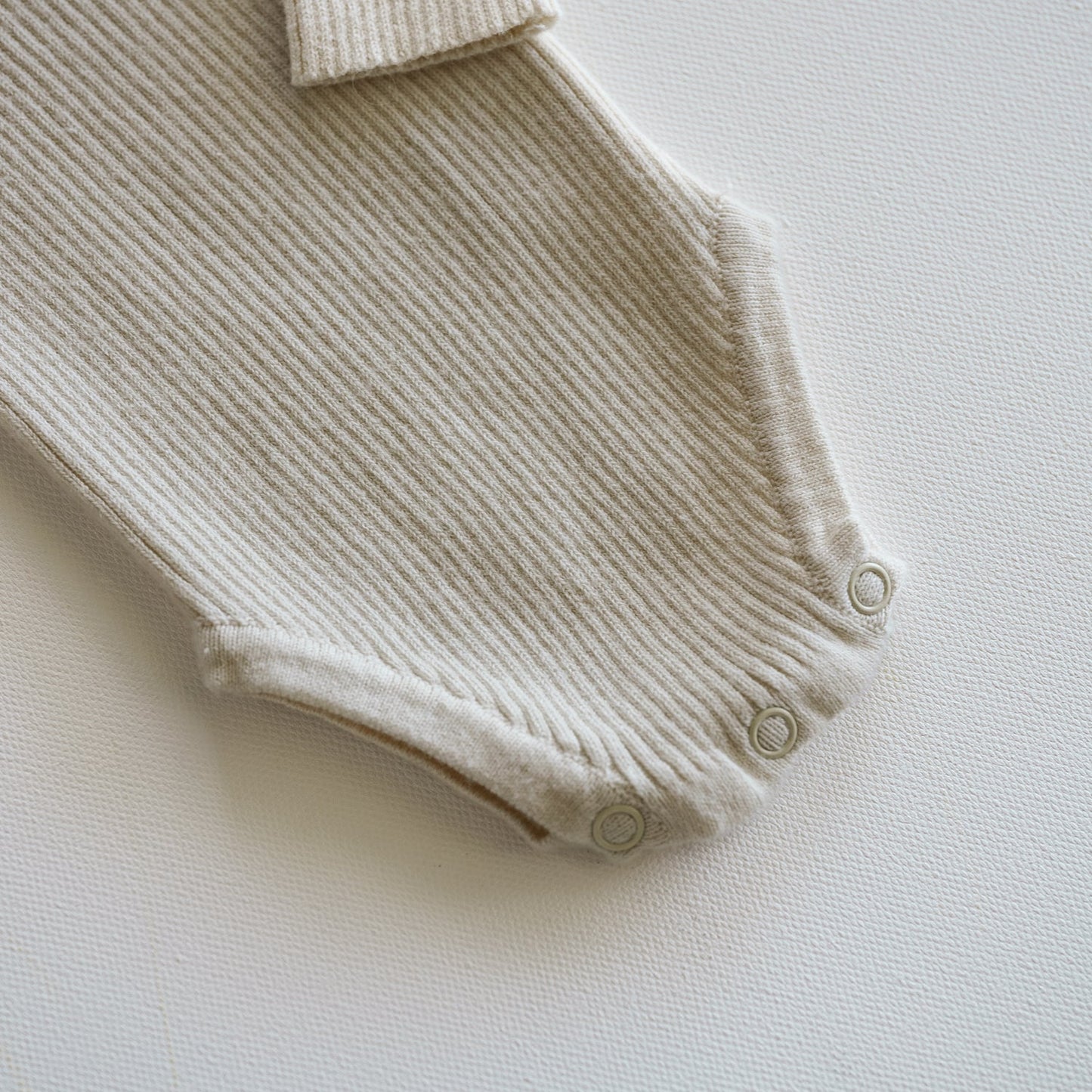 Beige ribbed baby romper on a light background