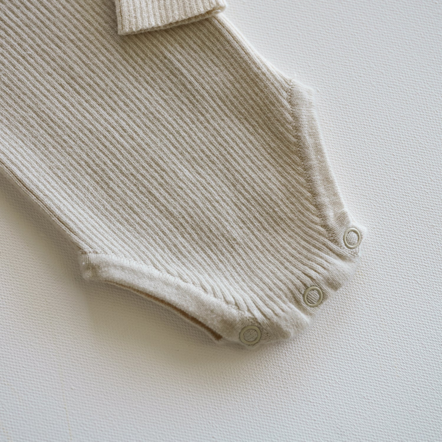 Beige ribbed baby romper on a light background